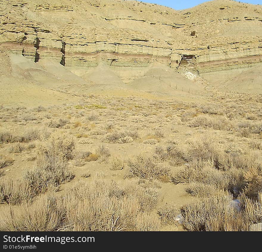 Scenery in Duschene County, Southern Utah.  kinda dry and desolate. not much color except for blue sky. Formations in the cliffs from rain.