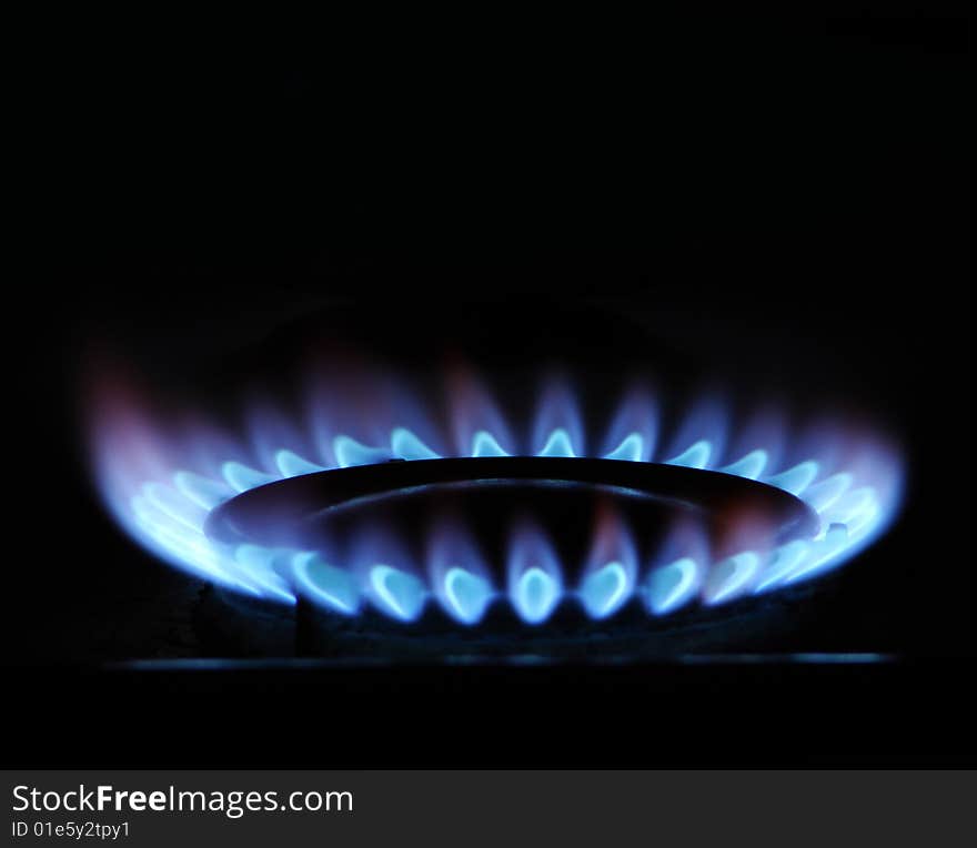 Blue flame of gas over black background