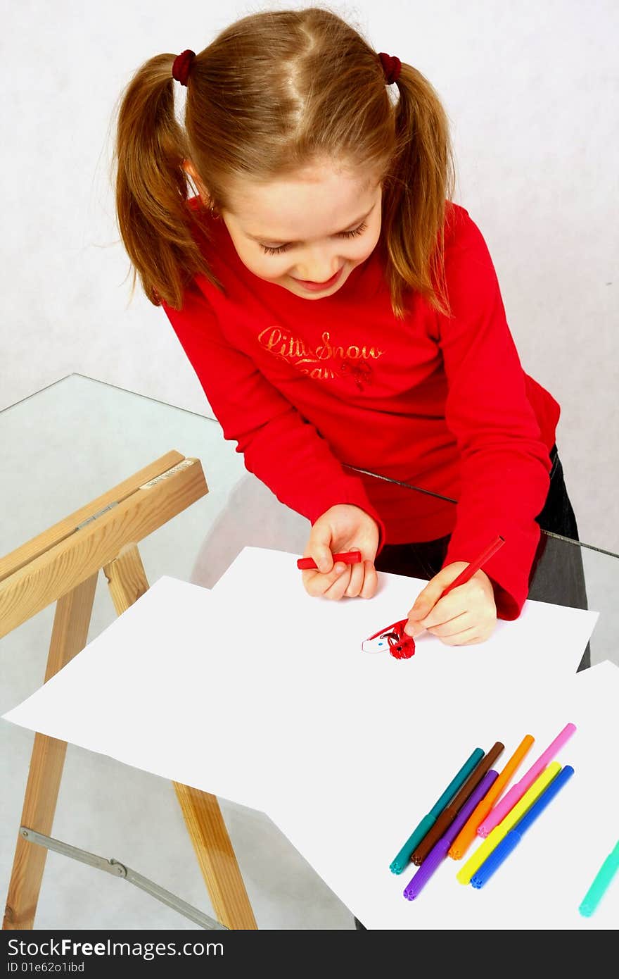 Young girl in red drawing an image. Isolated. Young girl in red drawing an image. Isolated.