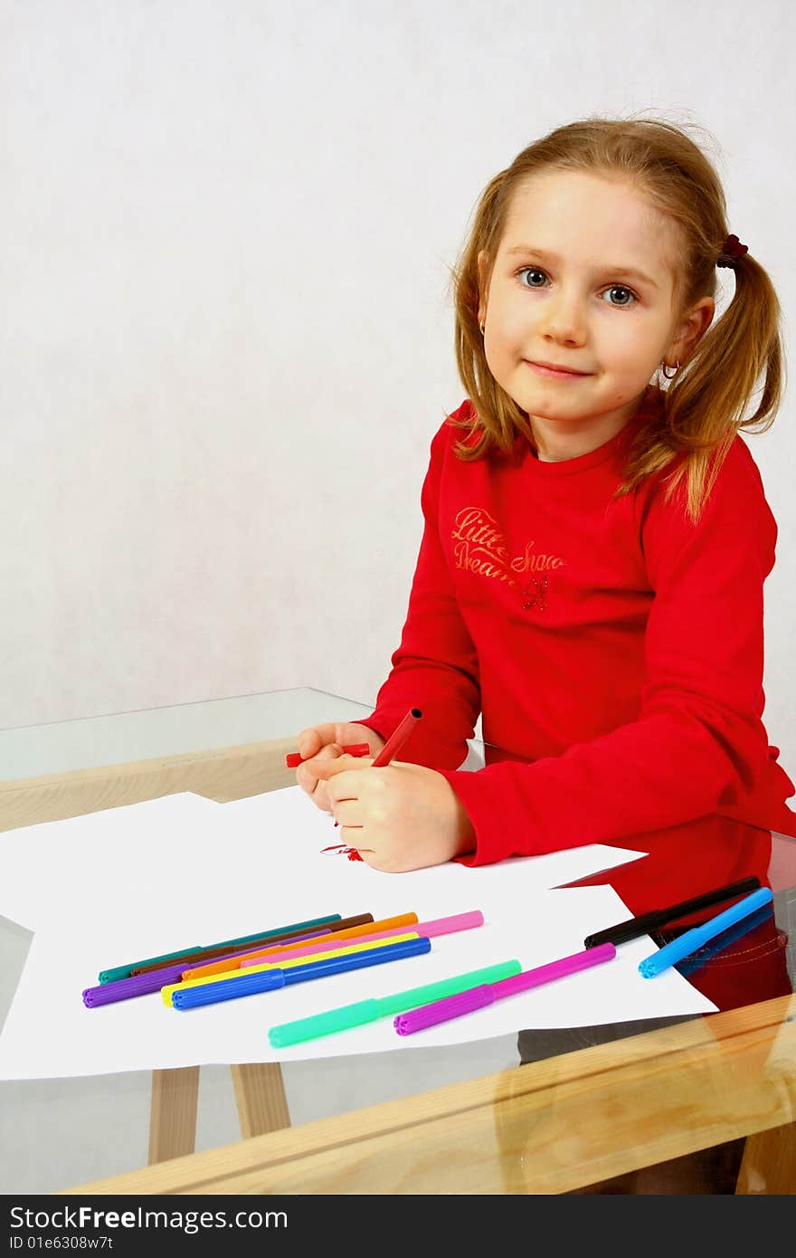 Young girl in red drawing an image with felt-pen. Isolated. Young girl in red drawing an image with felt-pen. Isolated.