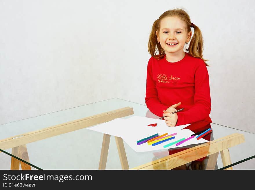 Young girl in red drawing an image with felt-pen. Isolated. Young girl in red drawing an image with felt-pen. Isolated.