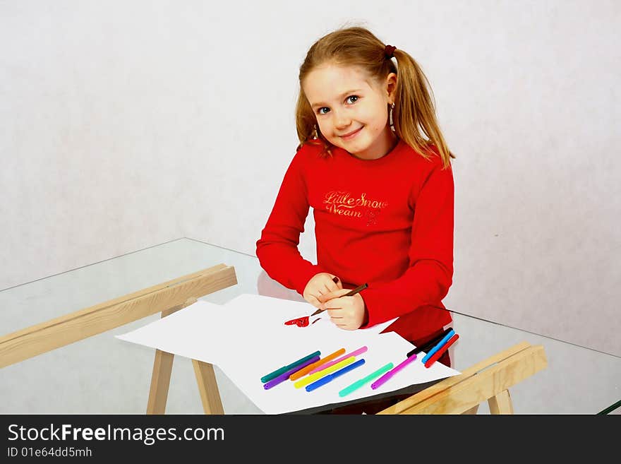 Young girl in red drawing an image with felt-pen. Isolated. Young girl in red drawing an image with felt-pen. Isolated.