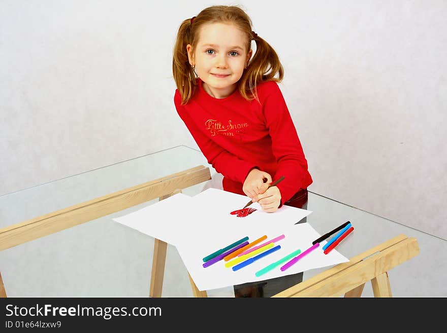 Young girl in red drawing an image with felt-pen. Isolated.