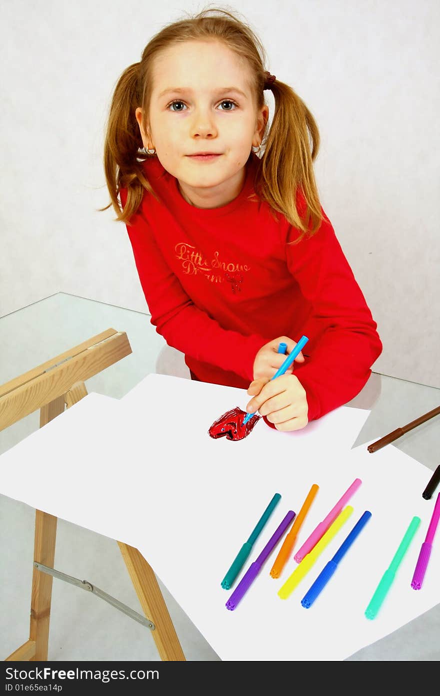 Young girl in red drawing an image. Isolated. Young girl in red drawing an image. Isolated.