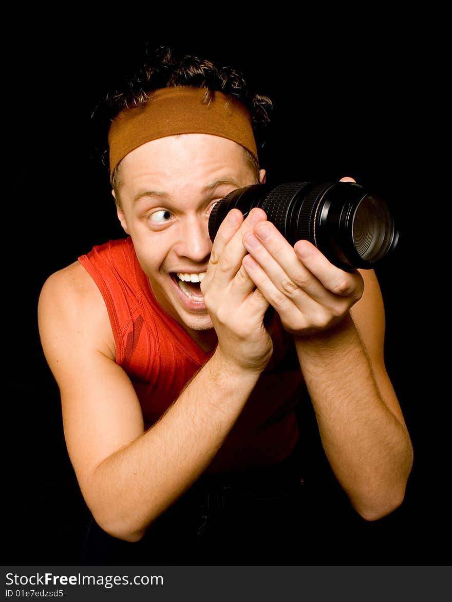 Young man looks through camera lens over black