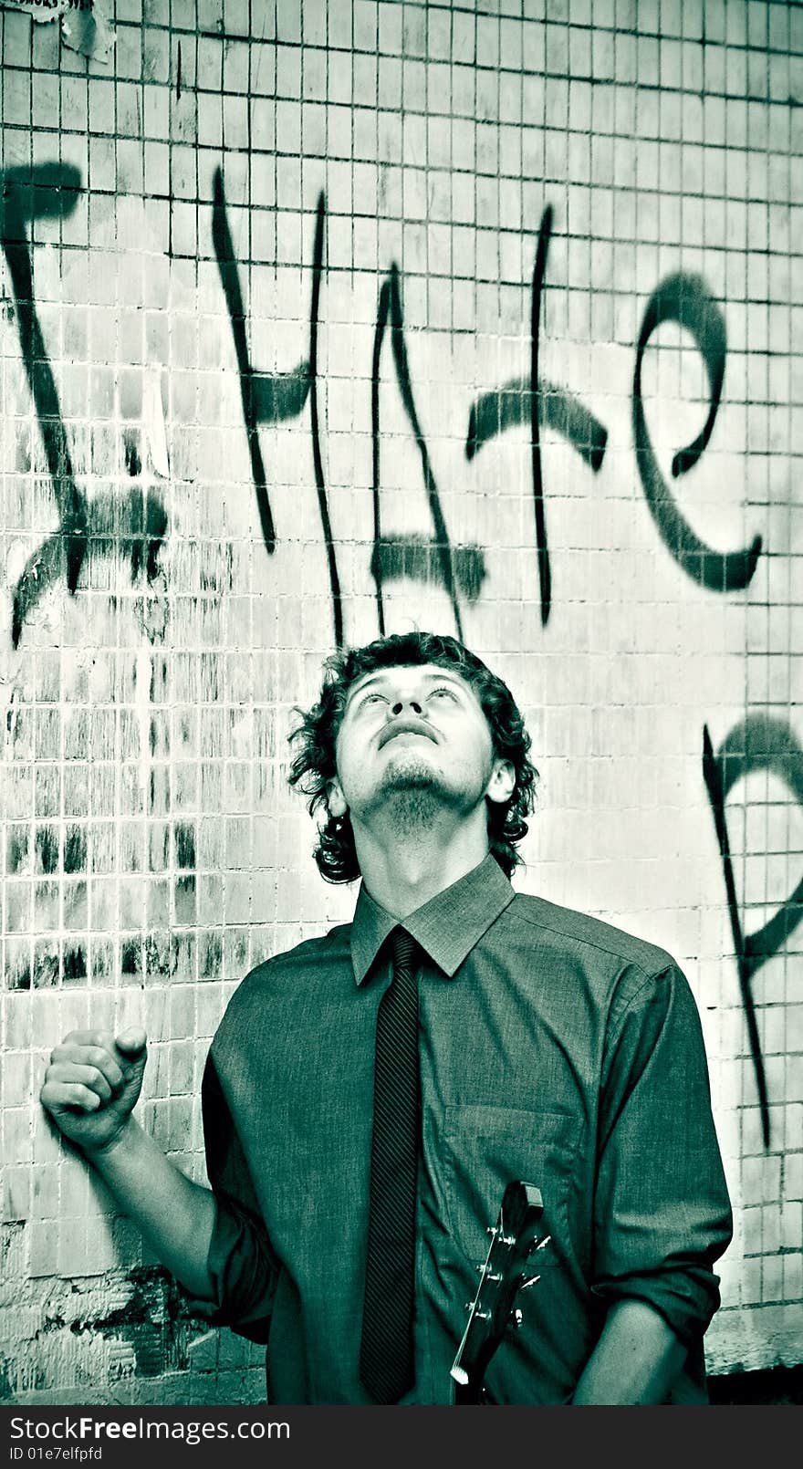 Monochrome lomo picture of business styled man with guitar over brick wall with graffiti