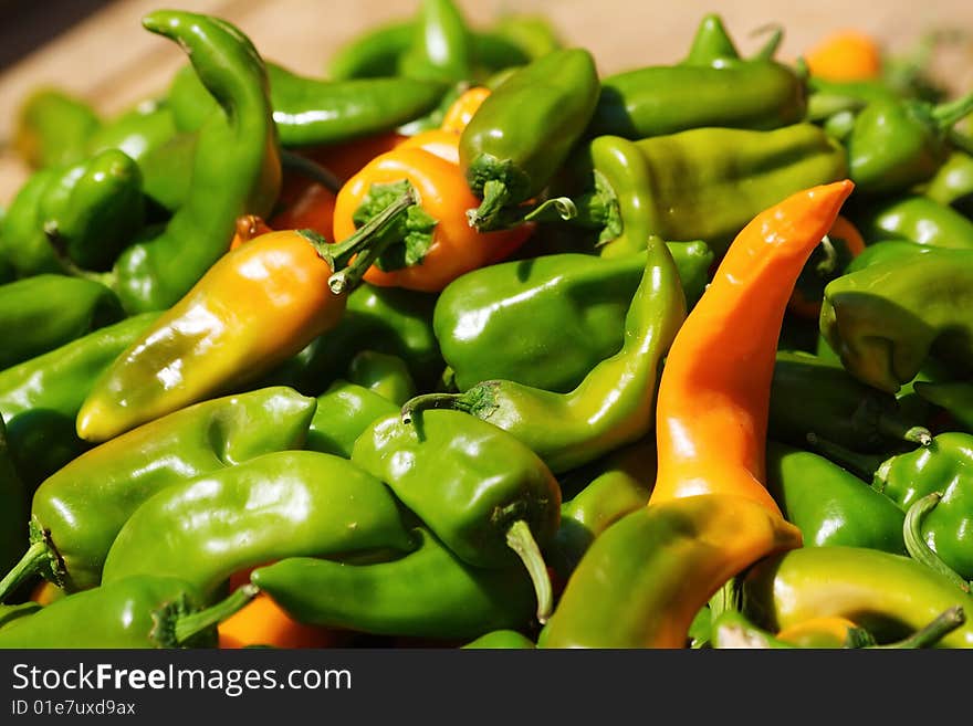 Pile of green chili peppers and some orange ones