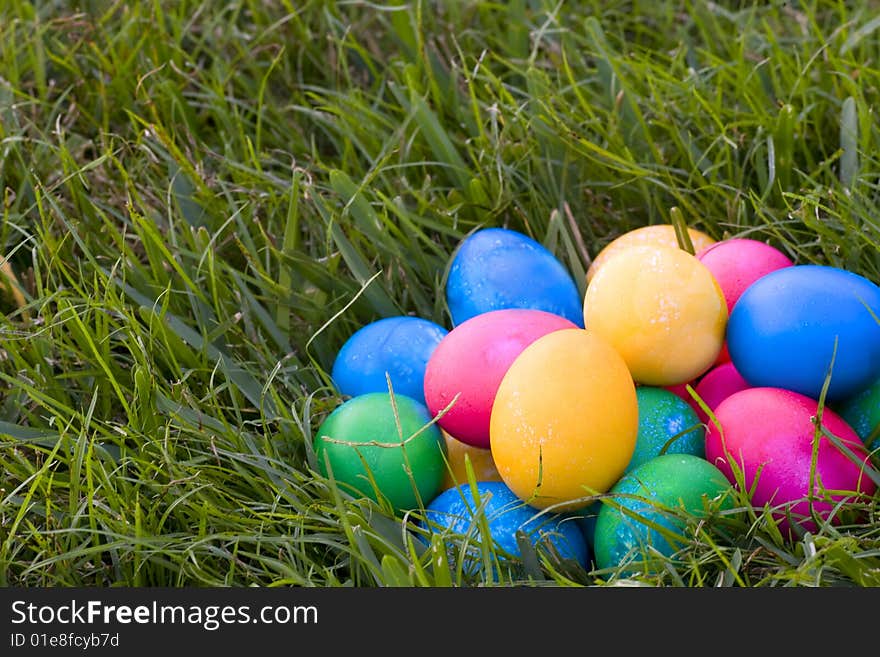 Stack of brightly colored easter eggs sitting in the grass