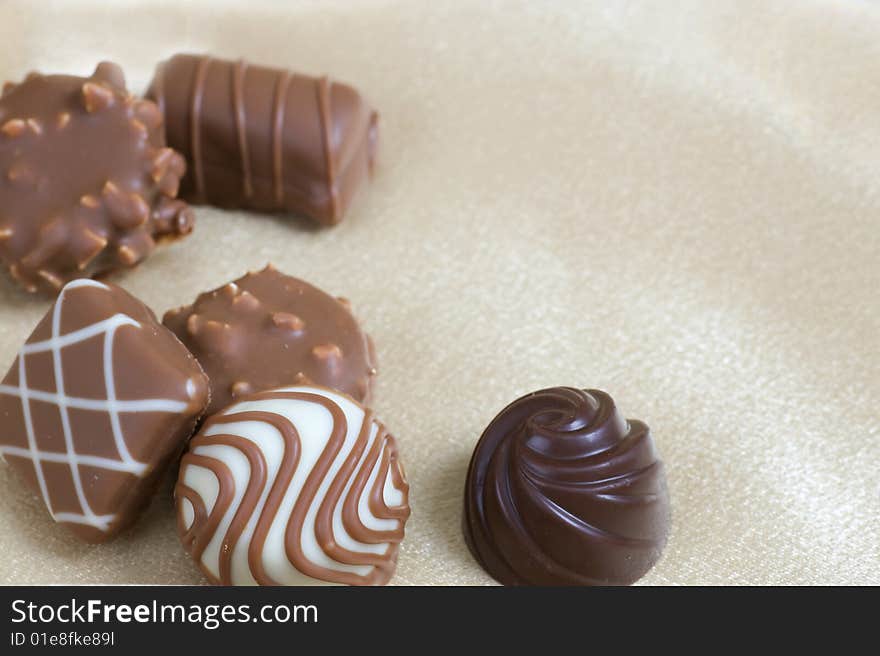 Chocolate candies laid out as a border on ivory satin