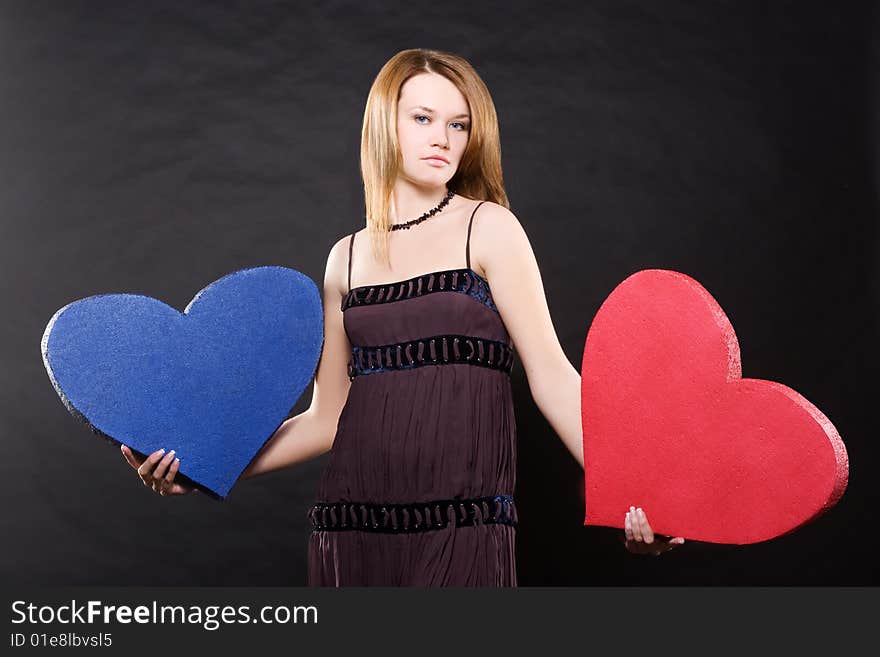 Pretty girl in dress dancing with two hearts  over black background