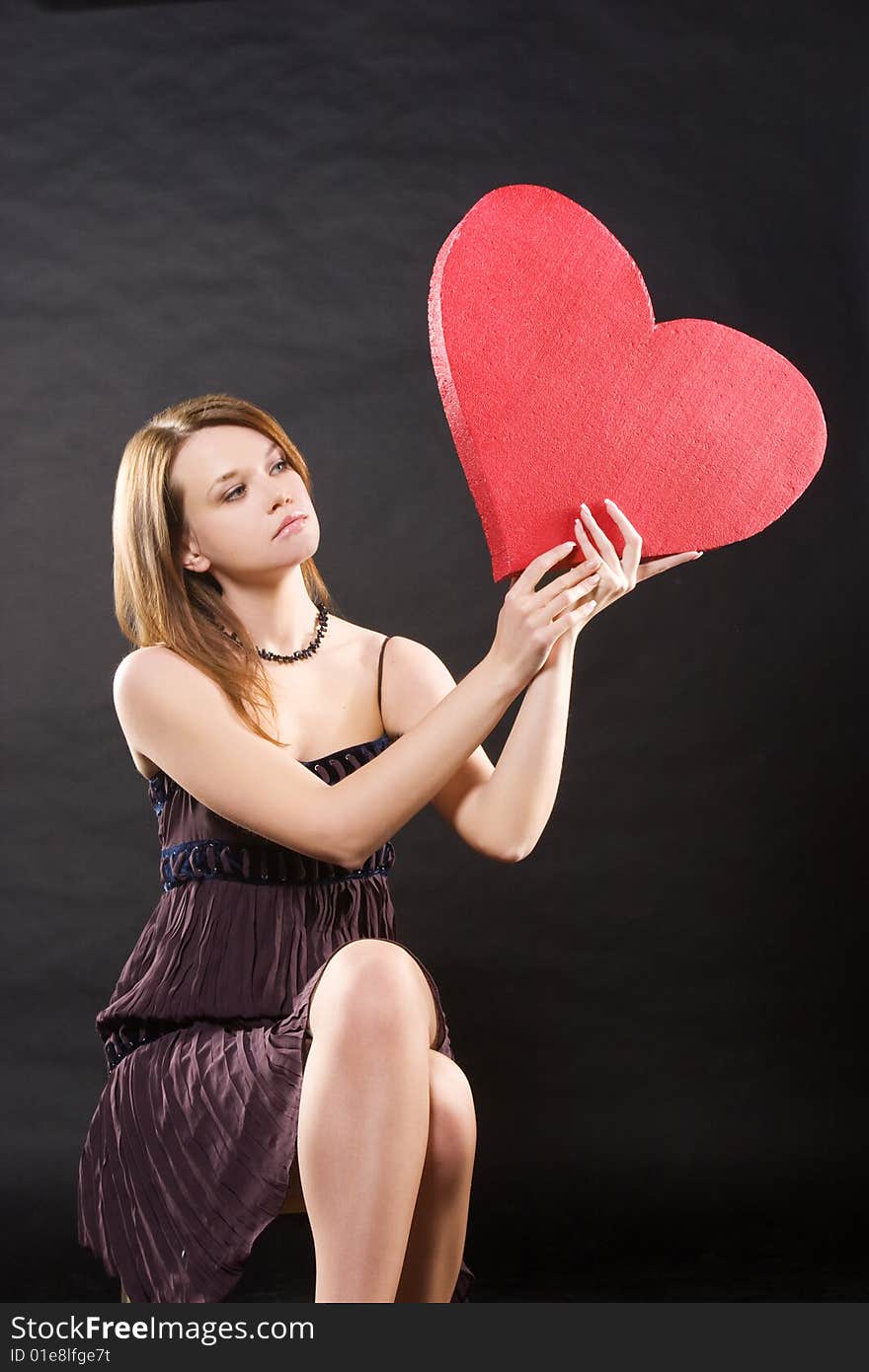 Girl in dress sitting with red heart