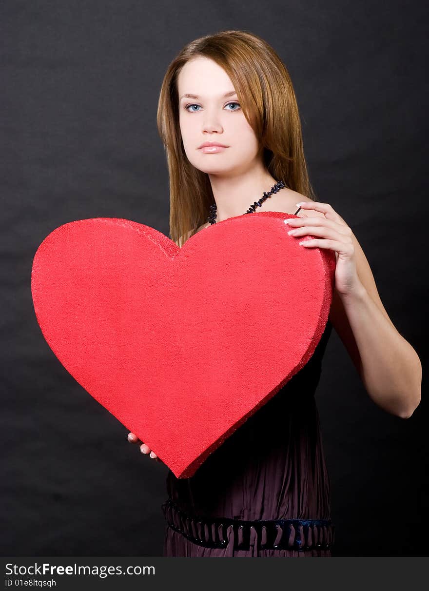 Girl holding red heart  over black background