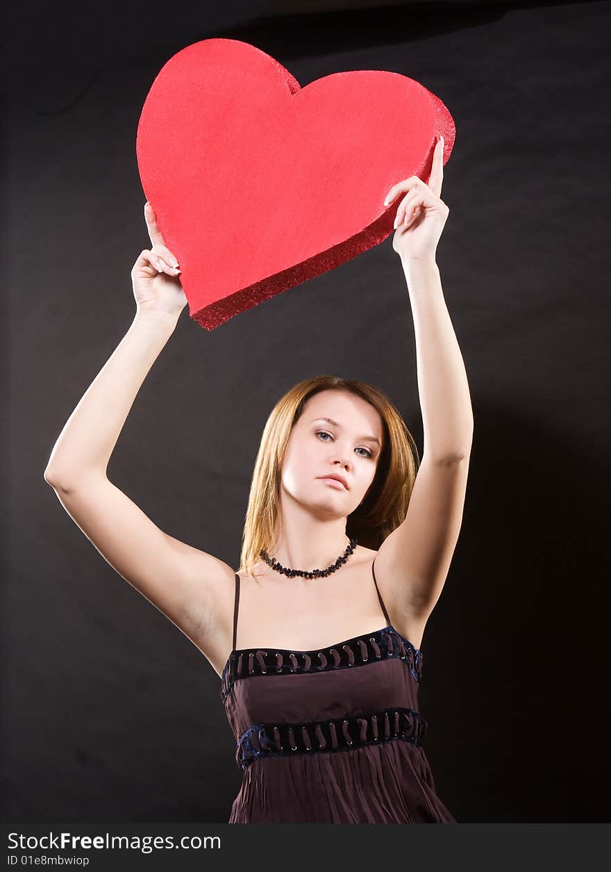 Cool girl in dress with red heart  over black background