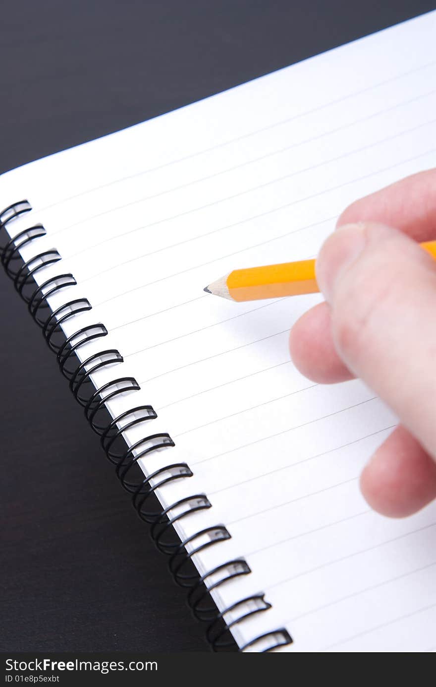 Writing in a blank spiral-bound notebook with yellow pencil. Writing in a blank spiral-bound notebook with yellow pencil.