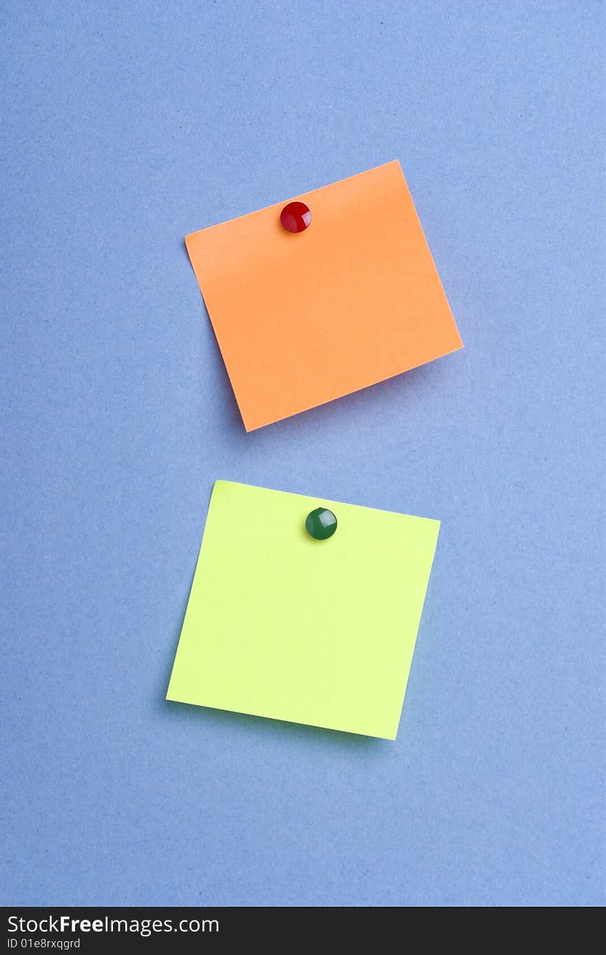 Two post it notes with drawing pins on blue background. Two post it notes with drawing pins on blue background