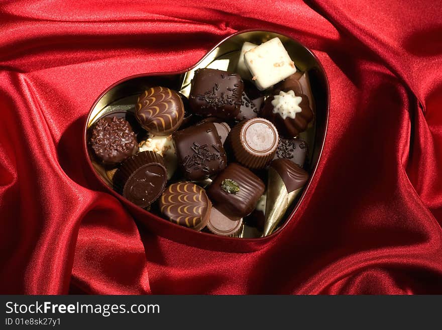 Golden chocolates box on red satin background. Golden chocolates box on red satin background