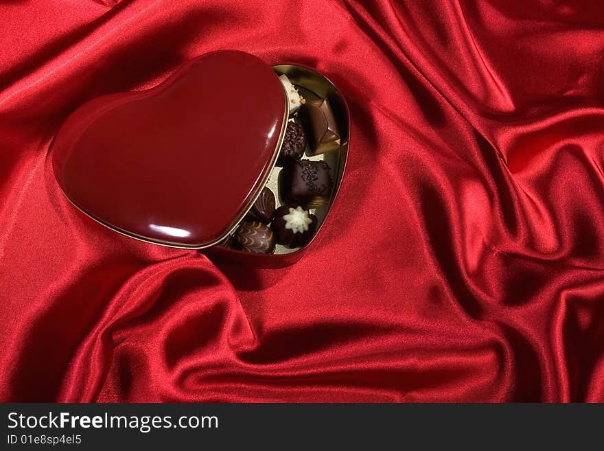 Heart Shaped Box of Candy on red satin background