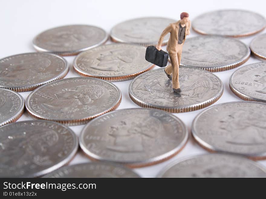 Miniature business man with briefcase running on quarters. Miniature business man with briefcase running on quarters.