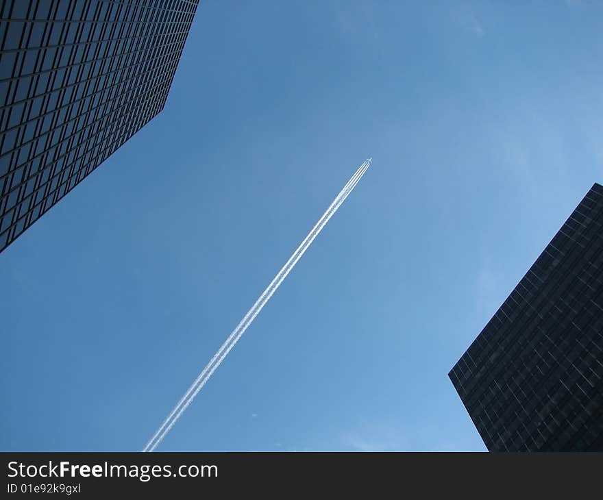 The plane between skyscrapers in the blue sky