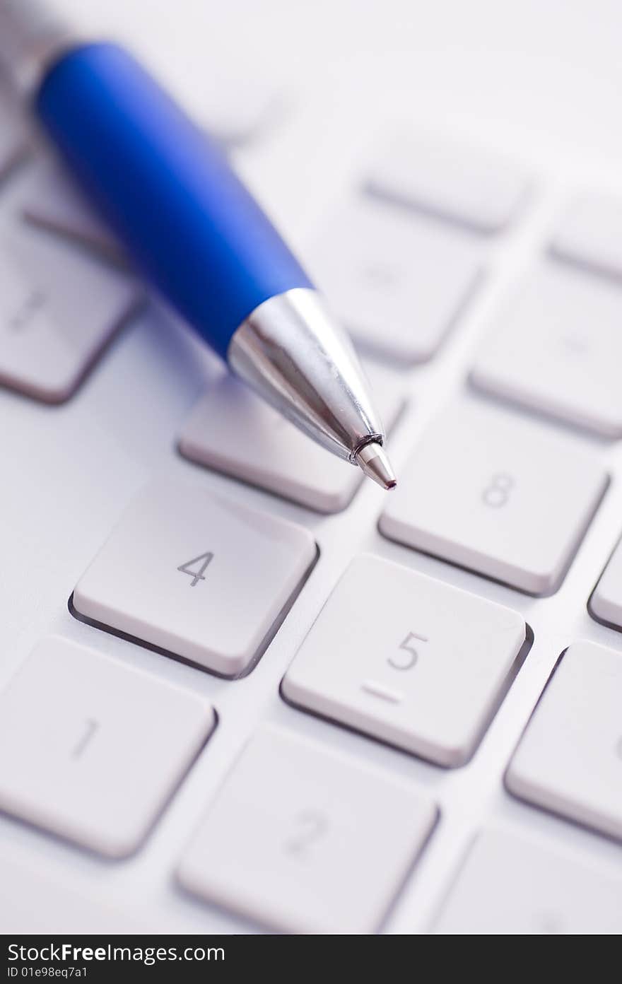 White keyboard and blue pen on the table