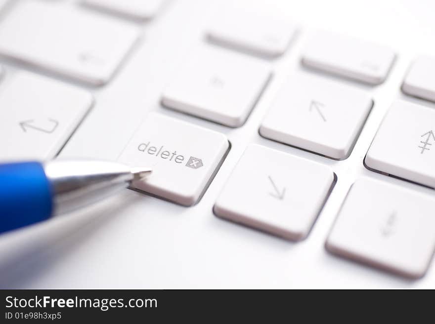 White keyboard and blue pen on the table