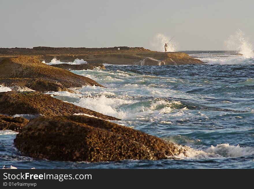 One active angler fishing in the Indian Ocean during high tide at Botany Bay, NSW, Australia