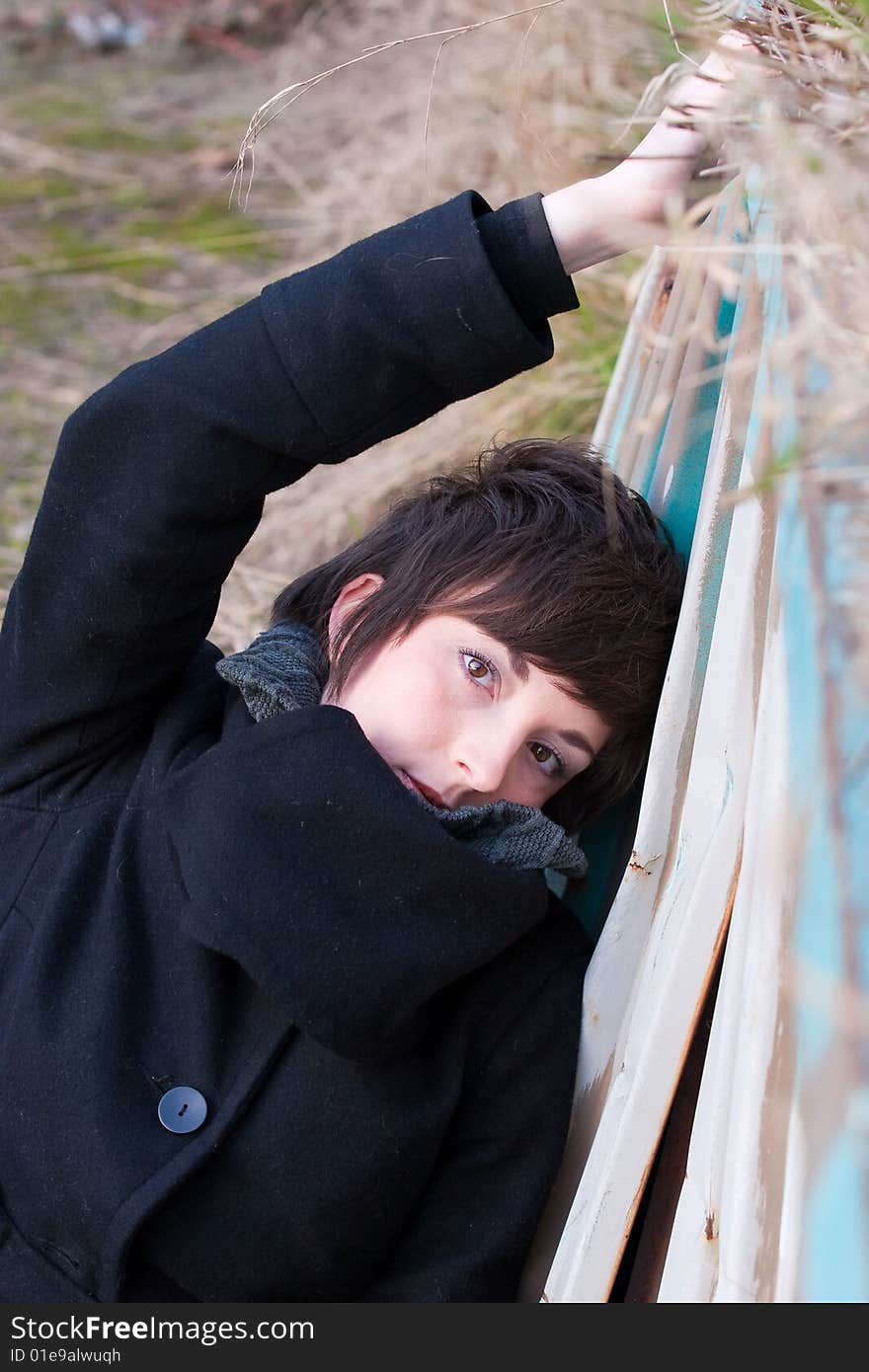 A fashionable portrait of a female in a jacket at an old trainyard against a blue wall. A fashionable portrait of a female in a jacket at an old trainyard against a blue wall.