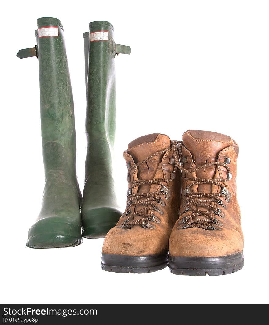 Old walking boots and green Wellington boots isolated against a white background