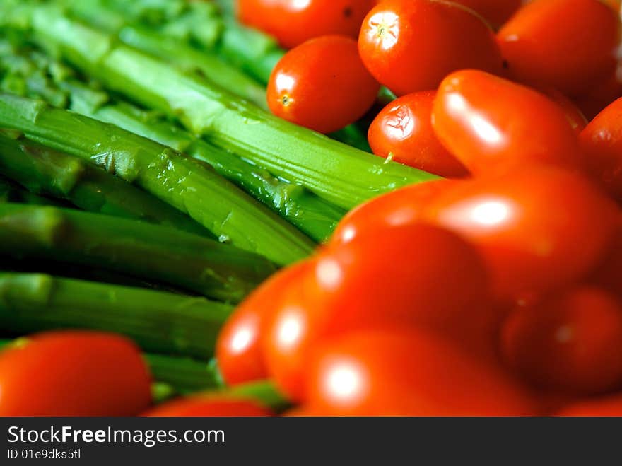 A close up image of ripe vibrant asparagus and cherry tomatoes. A close up image of ripe vibrant asparagus and cherry tomatoes