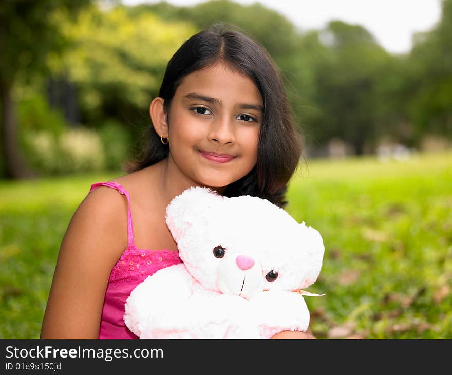 Asian origin girl in the garden with her pink teddy bear. Asian origin girl in the garden with her pink teddy bear