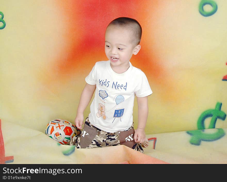 Boy's sitting on the ground is , his nearby put a ball. Boy's sitting on the ground is , his nearby put a ball.