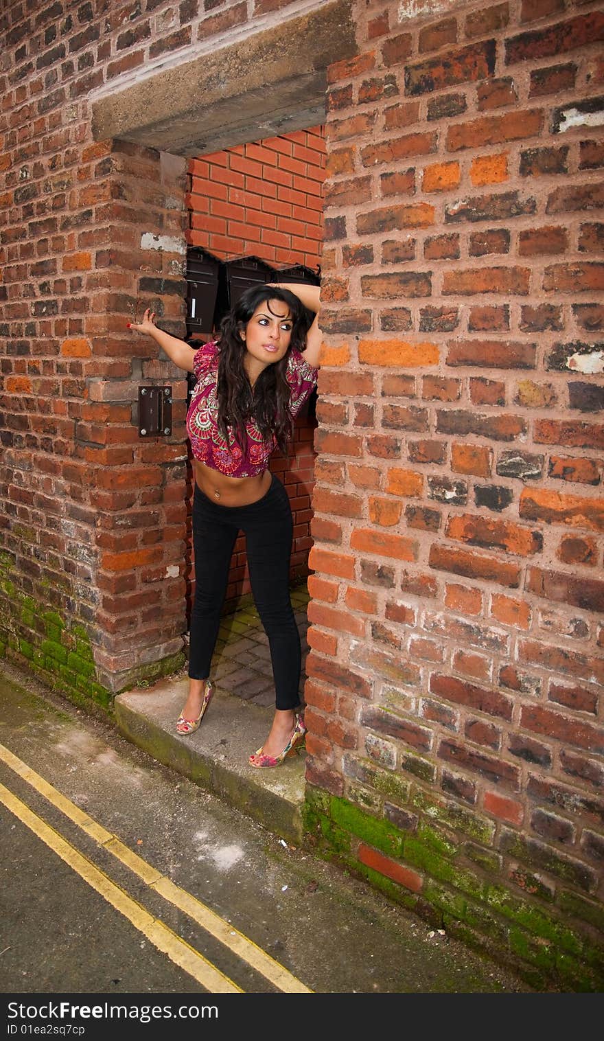 A sexy young Asian female posing in the doorway of a city center building.