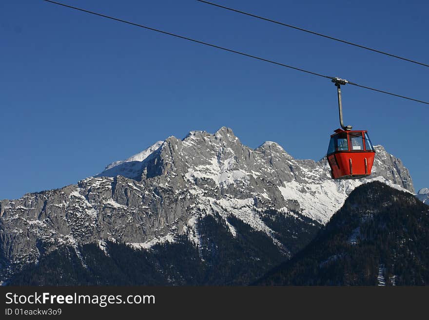 Red gondala in the mountains against a blue sky. Red gondala in the mountains against a blue sky