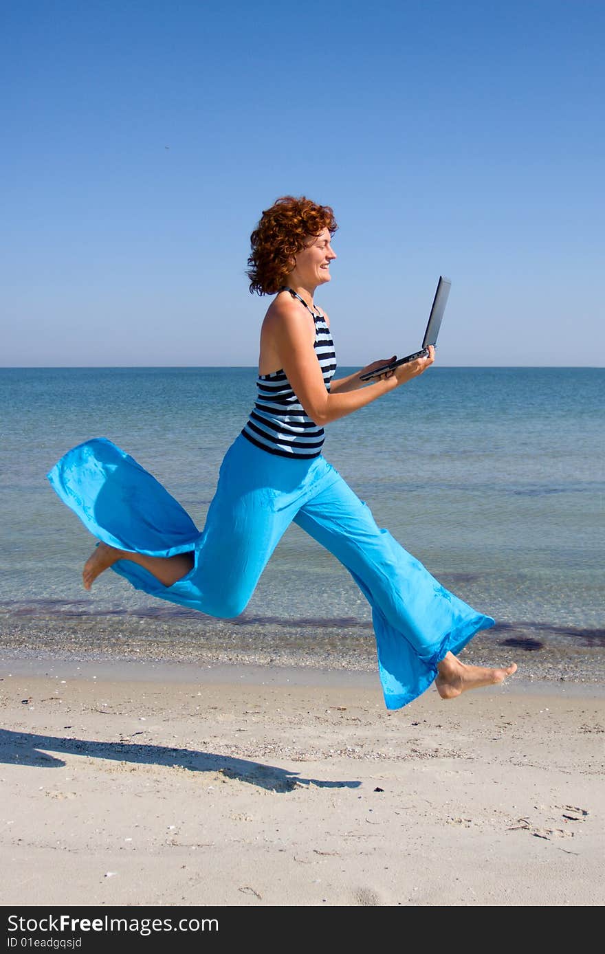 Girl with laptop running along sea coast. Girl with laptop running along sea coast