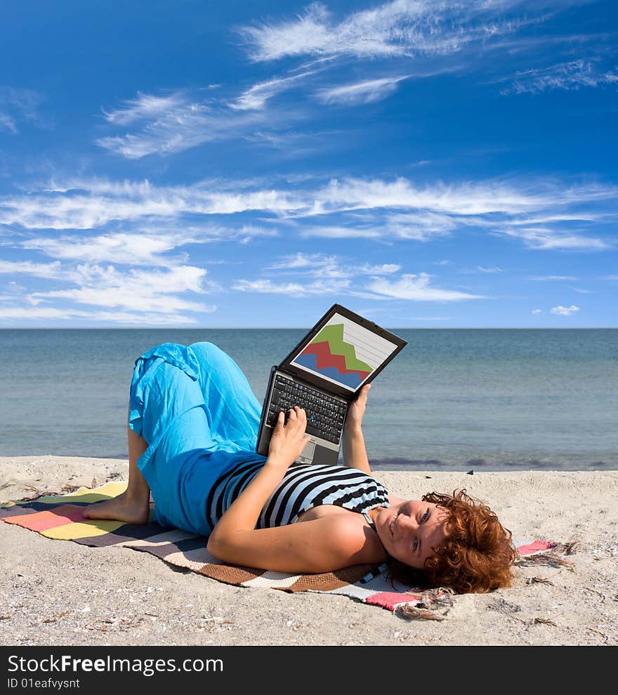 Girl working on laptop near of sea