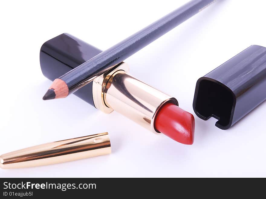 Red lipstick and black crayon on white background