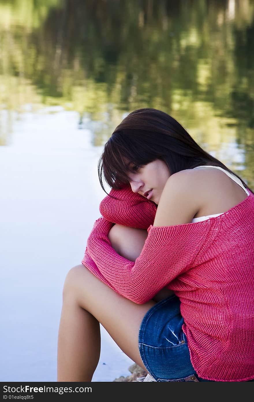 Young thoughtful woman against water background.