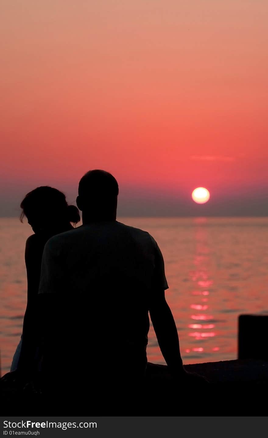 Two people sitting at the beach and watching sunset. Two people sitting at the beach and watching sunset