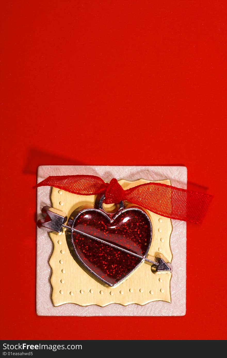 Red metal heart with ribbon is glue on the design ribbon