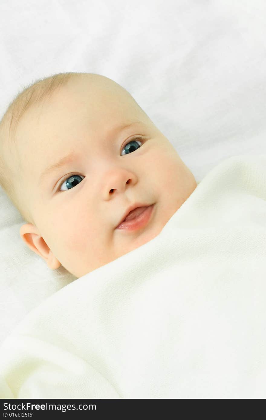 Portrait of a cute four months old baby boy on the bed with white sheets