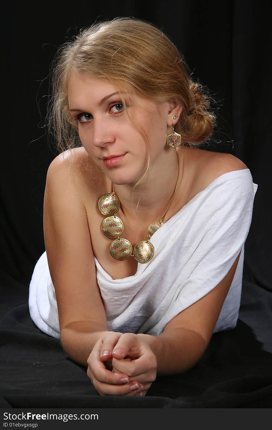 The woman in a white fabric lays on a black background