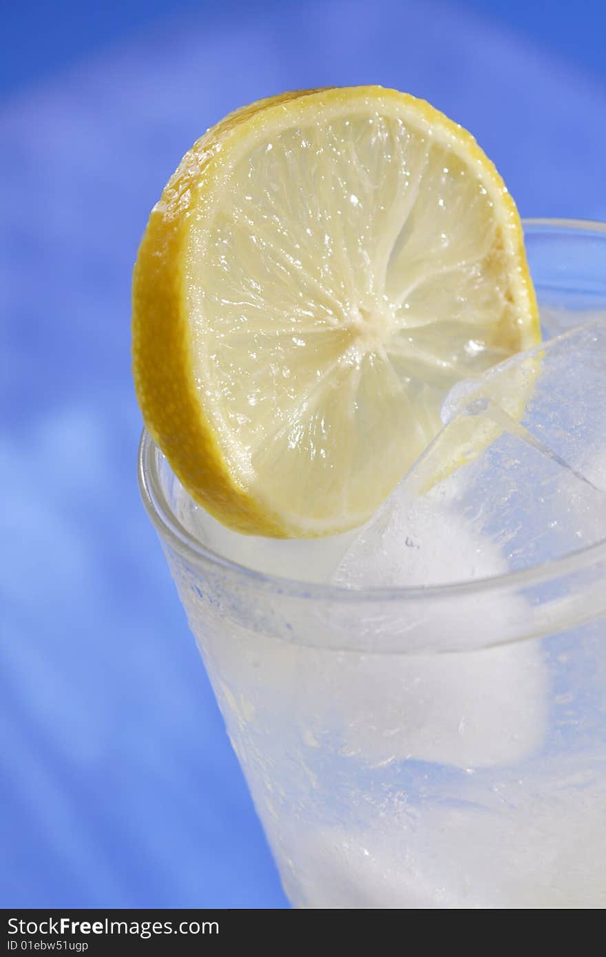 Lemon slice resting in glass of ice water. Lemon slice resting in glass of ice water