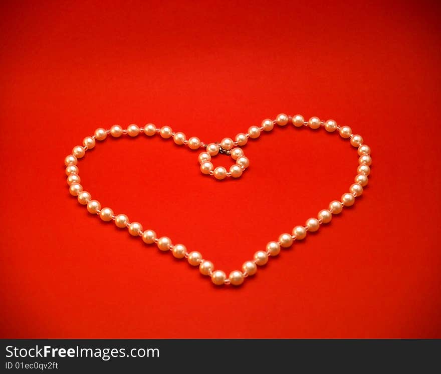 Heart Made Of Pearl Necklace On Red Background