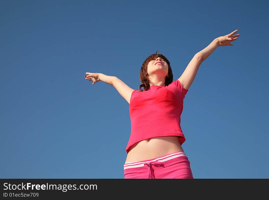 Young girl with raised hands on blue sky background