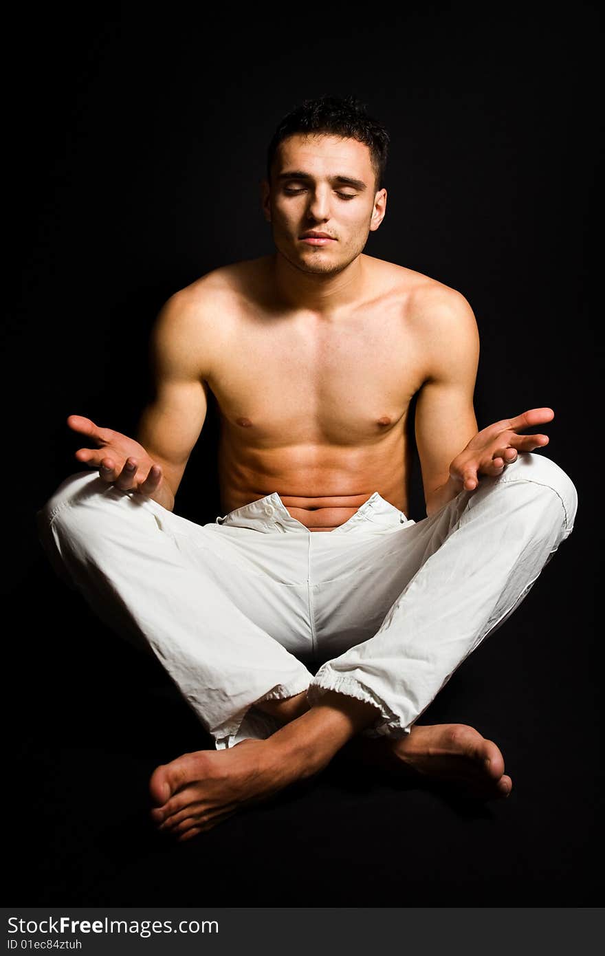 Young man in lotus yoga position isolated on black