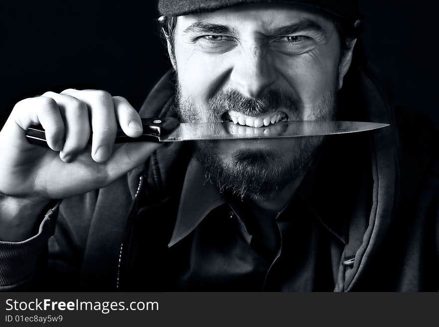 Tough angry guy biting from sharp knife. Tough angry guy biting from sharp knife