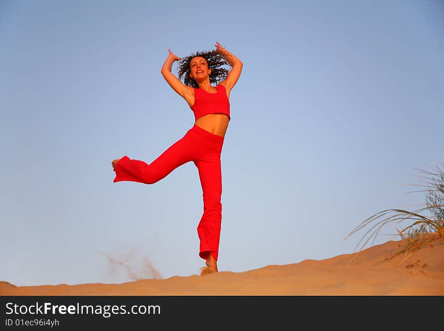 Young woman in red runs on sand. Young woman in red runs on sand