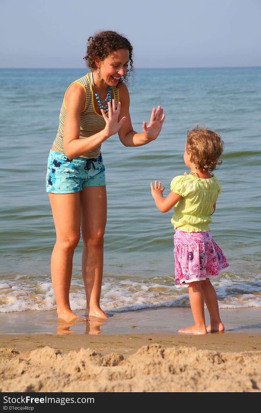 Mother plays with daughter on beach, okee-dokee