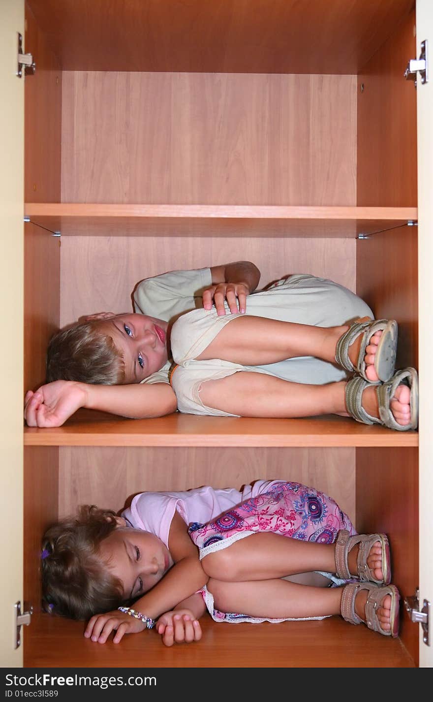 Two children sleeps on shelves in cabinet