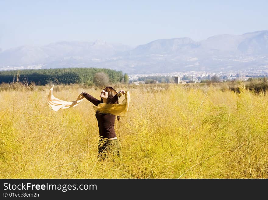 Young woman dancing with scarf in a field. Young woman dancing with scarf in a field.